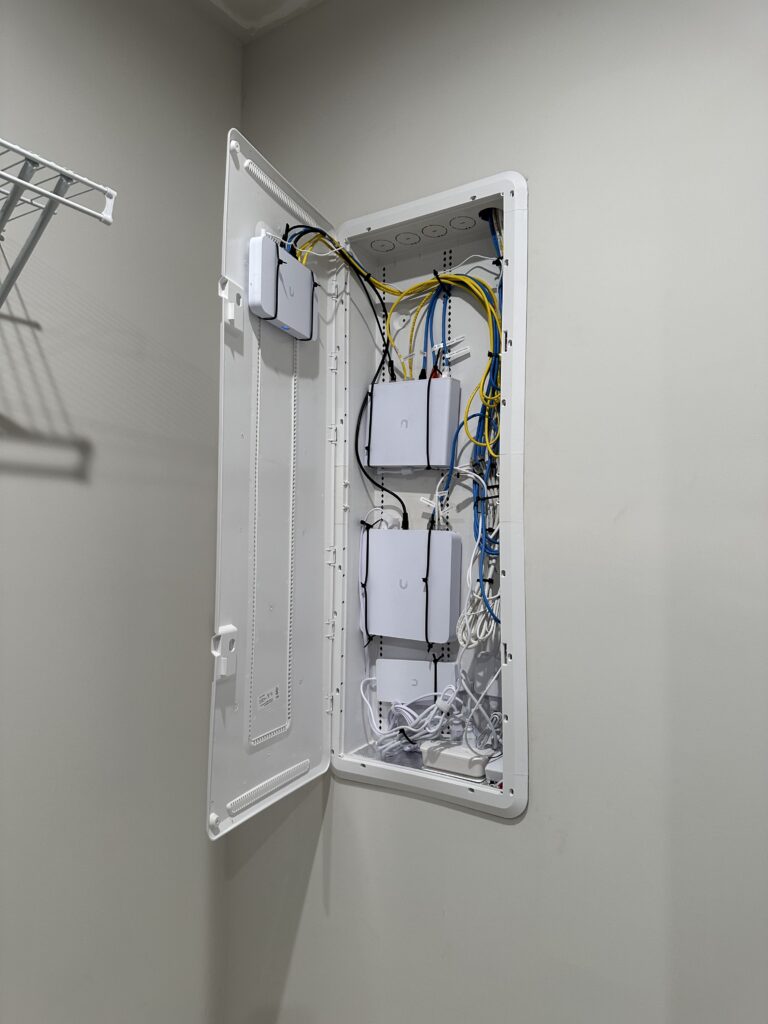 Open structured media enclosure containing network equipment and organized Ethernet cabling.